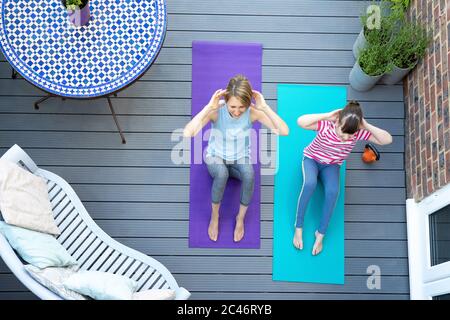 Vista aerea di madre e figlia che si esercitano insieme a casa sul ponte Foto Stock