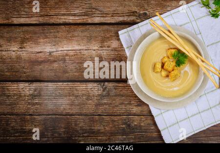 Zuppa di pollo cremosa al cavolfiore in ciotola grigia guarnita con crostini croccanti e bastoncini di pane italiani. Vista dall'alto. Foto Stock
