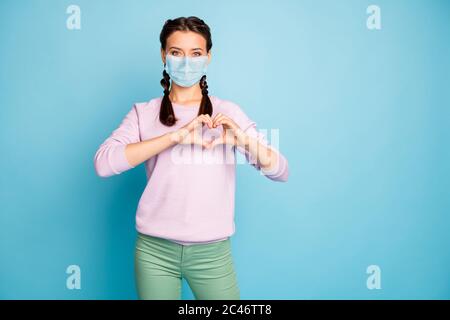 Ritratto di lei bella ragazza sana e attraente indossare garza maschera di sicurezza che mostra il segno cuore influenza luca grippe terapia di recupero isolato luminoso vivace Foto Stock