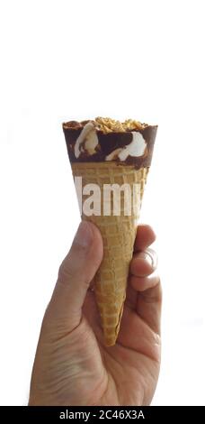 Mano dell'uomo che tiene un cono gelato alla vaniglia ricoperto di cioccolato con arachidi su sfondo bianco Foto Stock