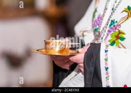 Sacerdote che tiene una coppa d'oro con vino nelle mani Foto Stock