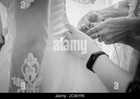 bridesmaids stringono l'abito della sposa in bianco e nero Foto Stock