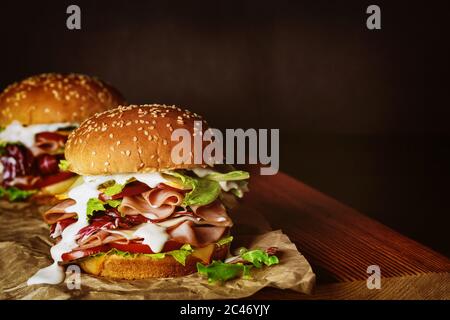 Deliziosi panini con verdure fresche, formaggio e prosciutto su tavola di legno. Foto Stock