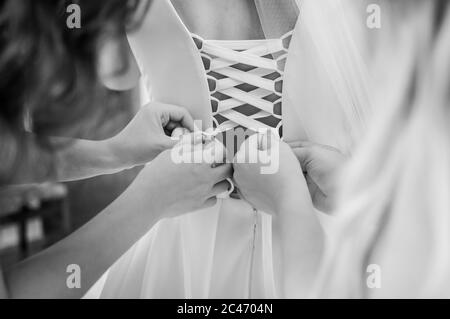 bridesmaids stringono l'abito della sposa in bianco e nero Foto Stock