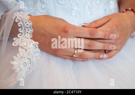 Belle mani di donna che si stende su un vestito bianco, anello di fidanzamento, manicure dolce, pronto per la cerimonia di matrimonio Foto Stock