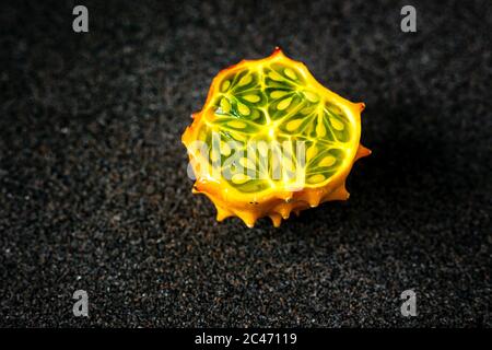 Frutta Kiwano tagliata a metà su fondo grigio scuro Foto Stock