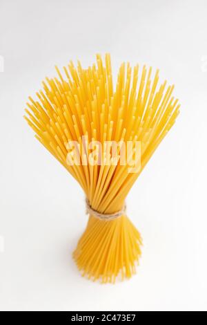 Un mazzo di spaghetti crudi legati con spago su bianco Foto Stock