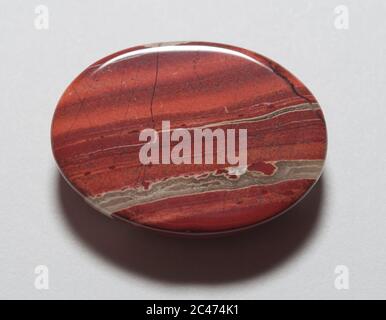 Cabochon naturale rosso agata con strisce su sfondo bianco Foto Stock