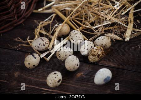 Uova di quaglia. Uova in paglia, su sfondo di legno Foto Stock