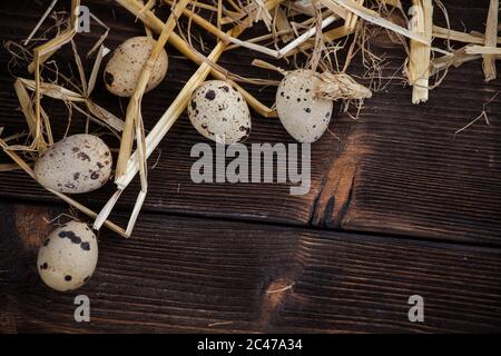 Uova di quaglia. Uova in paglia, su sfondo di legno Foto Stock