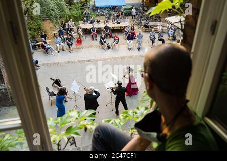 Berlino, Germania. 23 Giugno 2020. Uno spettatore guarda un concerto di cortile eseguito da membri dell'orchestra Staatskapelle Berlin a Berlino, capitale della Germania, il 23 giugno 2020. Credit: Peter Adamik/Xinhua/Alamy Live News Foto Stock