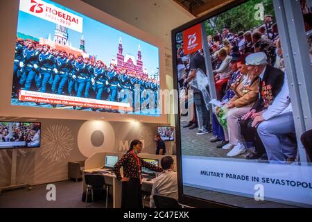 Mosca, Russia. 24 giugno 2020 trasmissione della parata militare in onore del 75° anniversario della vittoria nella seconda guerra mondiale da Piazza Rossa (sinistra) e Sevastopol (destra) su schermi nel Centro Stampa Internazionale dell'evento a Mosca, Russia Foto Stock