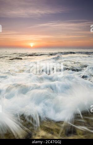 Immagine verticale delle ondate di oceano ipnotizzanti sotto un cielo viola Foto Stock