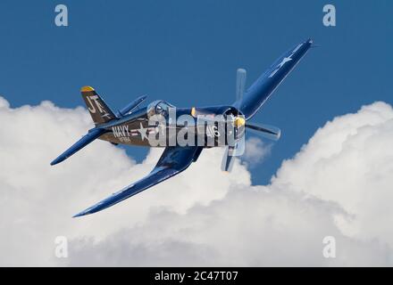 Un aereo da combattimento Vought F4U Corsair della seconda Guerra Mondiale che vola sopra le nuvole in un cielo blu profondo. Foto Stock