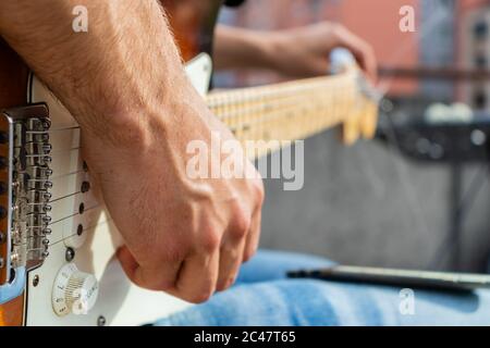 Primo piano del chitarrista mentre sta sintonizzando la sua chitarra prima del concerto. Foto Stock