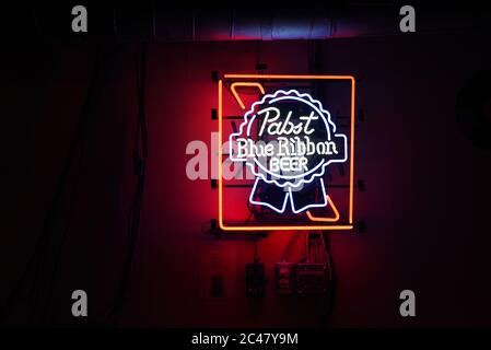 Un cartello al neon Pabst Blue Ribbon Beer pende sul muro di un bar e nightclub scuro Foto Stock