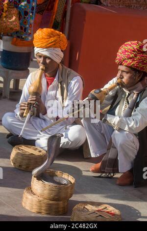 I Charmers del serpente stanno giocando e ondeggiando intorno ad uno strumento denominato pungi per hypnotize una cobra in Jaipur India Foto Stock