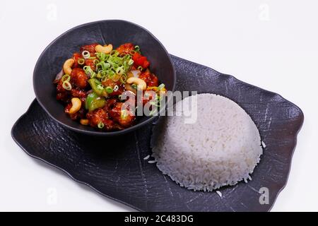 pollo cinese kung pao con riso jasmine in un piatto nero Foto Stock