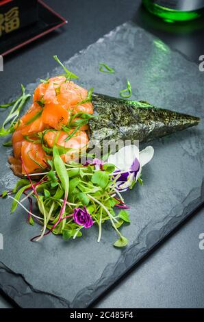 Sushi. Cucina tradizionale giapponese, salmone di alta qualità Temaki decorato in un ambiente elegante. Foto verticale. Foto Stock