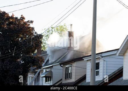 Fumo antincendio a più allarmi che si alza dalle case. Due case catturate sul fuoco hanno inviato fumo bianco nell'aria come bruciano. Grande casa residenziale fuoco. Foto Stock