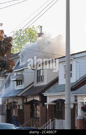 Casa sul fuoco con fumo bianco pesante che si alza dai tetti. Casa residenziale fie primo piano. Foto Stock