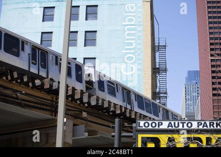 CHICAGO, STATI UNITI - 18 aprile 2020: Il treno CTA passa sopra la testa con il Columbia College Building sullo sfondo in una giornata di sole brillante in th Foto Stock