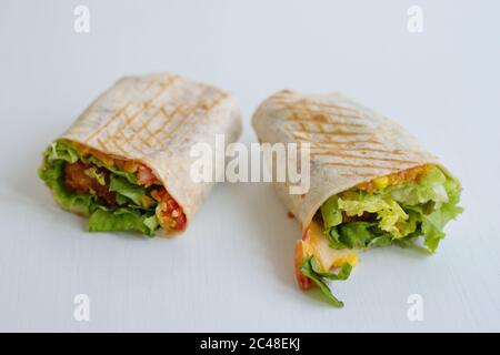 Tortilla con carne di pollo fritto e verdure isolate su sfondo bianco Foto Stock