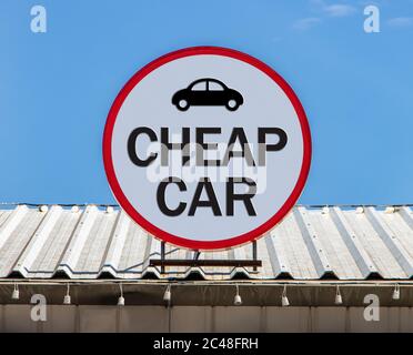 Un cartellone circolare con testo Cheap car, è installato su un tetto. Offerta di veicoli economici. Foto Stock