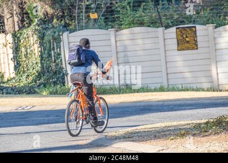 Alberton, Sudafrica - l'uomo nero non identificato usa la sua bicicletta per il trasporto per ottenere alla sua prossima immagine di lavoro giardino in formato orizzontale Foto Stock