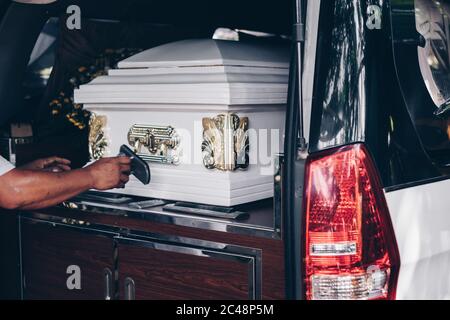 Primo piano di un casket caricato in un'auto o un allenatore di piano funerale o hearse per la processione funeraria. Messa a fuoco selettiva. Foto Stock