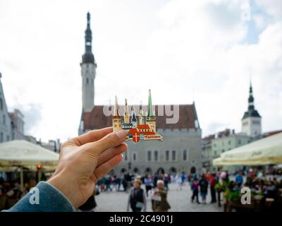 Tallinn, Estonia- 20.07.2019: Mano maschile con magnete Tallinn Estonia. Vista della città vecchia e Piazza del Municipio in estate Foto Stock
