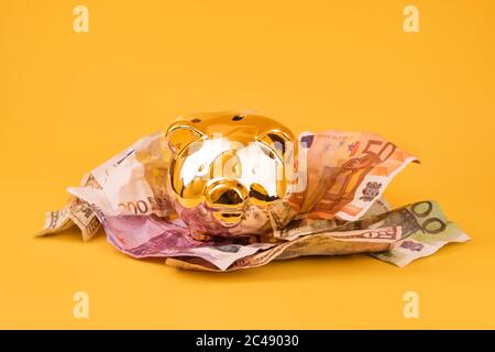 Golden piggy banca con denaro contante, euro e banconote in dollari. Scatola di soldi d'oro, risparmi enormi, accumulazione di soldi. Moneypig, risparmio di denaro, Moneybox Foto Stock