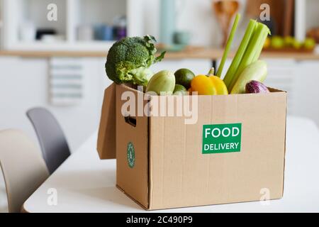 Primo piano di verdure fresche in scatola di cartone sul tavolo consegnato a casa Foto Stock