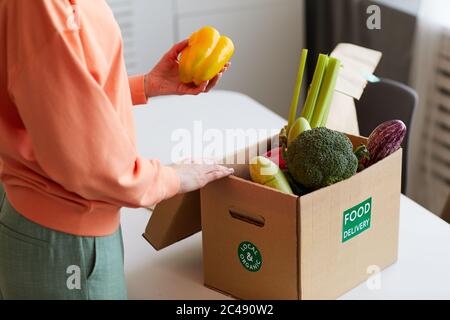 Primo piano di giovane donna che prende verdure fresche fuori dalla scatola in cucina Foto Stock