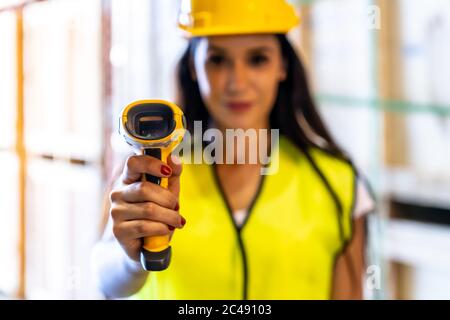 Primo piano di una donna caucasica bianca che lavora in magazzino tiene lo scanner a mano per controllare le scorte di magazzino nel magazzino di distribuzione. Tracciabilità FIFO inventato Foto Stock