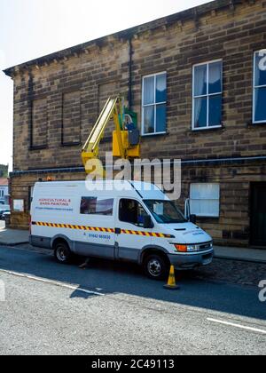 Uomo su un paranco idraulico che effettua una riparazione all'orologio sul Municipio Stokesley North Yorkshire Foto Stock