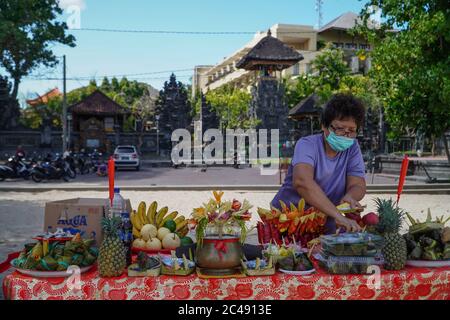 Badung, Bali, Indonesia. 24 Giugno 2020. Una donna indossa il facemask preparando gli attributi del rito. L'etnia balinese di Tionghoa ha tenuto le preghiere di Bak Cang dei riti di Peh Cun a Kuta Beach come offerte al Dio del mare in mezzo all'epidemia di Coronavirus di Covid-19. (Immagine di credito: © filo Dicky BisinglasiZUMA) Foto Stock