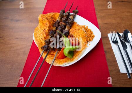 Carne di agnello kebab turca su spiedino. Con verdure e riso su un piatto di portata.Turkish SIS (sish) Kebab / shish kebab Foto Stock