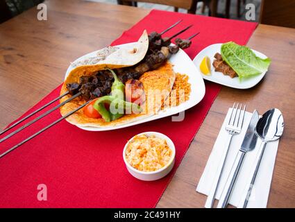 Carne di agnello kebab turca su spiedino. Con verdure e riso su un piatto di portata.Turkish SIS (sish) Kebab / shish kebab Foto Stock