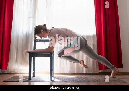 Donna che fa esercizi di spinta in su per il petto e le braccia di addestramento muscoli a casa Foto Stock
