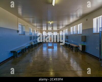 Robben Island, Sudafrica - 24 novembre 2019: Una cella carceraria comunale fiancheggiata da panchine, armadietti a muro e letti a castello in fondo Foto Stock