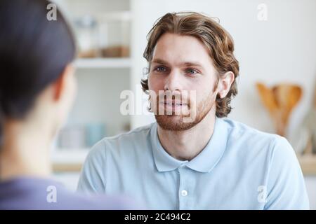 Giovane uomo che parla con la giovane donna mentre si siedono nella stanza Foto Stock