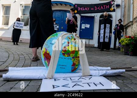 LEOMINSTER, REGNO UNITO - 25 GIUGNO 2020: I manifestanti sul cambiamento climatico si riuniscono nell'ambito di una giornata di proteste a livello nazionale con l'attenzione rivolta all'avvertimento "Delay = Death" a Leominster, Herefordshire, Regno Unito, il 25 giugno 2020. In coincidenza con la pubblicazione di un rapporto della commissione parlamentare britannica sul cambiamento climatico la sommaria processione composta da figure in costume con costumi in clessidra portava un modello bandito della terra alle porte del parlamentare locale. Credit: Jim Wood/Alamy Live News Foto Stock