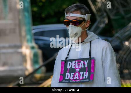 LEOMINSTER, REGNO UNITO - 25 GIUGNO 2020: I manifestanti sul cambiamento climatico si riuniscono nell'ambito di una giornata di proteste a livello nazionale con l'attenzione rivolta all'avvertimento "Delay = Death" a Leominster, Herefordshire, Regno Unito, il 25 giugno 2020. In coincidenza con la pubblicazione di un rapporto della commissione parlamentare britannica sul cambiamento climatico la sommaria processione composta da figure in costume con costumi in clessidra portava un modello bandito della terra alle porte del parlamentare locale. Credit: Jim Wood/Alamy Live News Foto Stock