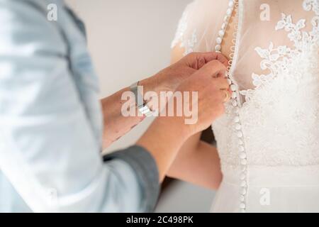 Primo piano di bottoni maschi l'abito bianco del femmina Foto Stock