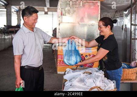 (200625) -- NINGMING, 25 giugno 2020 (Xinhua) -- Jiao Shengding acquista cibo per studenti in un mercato locale in Aidian Township della contea di Ningming, regione autonoma di Guangxi Zhuang, 23 giugno 2020. Jiao Shengding, 52 anni, è l'unico insegnante del villaggio di Zhangji, situato al confine tra Cina e Vietnam. Dopo essersi laureato alla scuola professionale secondaria della contea nel 1990, Jiao ha scelto di essere un insegnante presso il suo villaggio di Zhangji, città natale, e da allora ha insegnato lì per 30 anni. Negli ultimi tre decenni, ha insegnato più di 400 alunni, mo Foto Stock