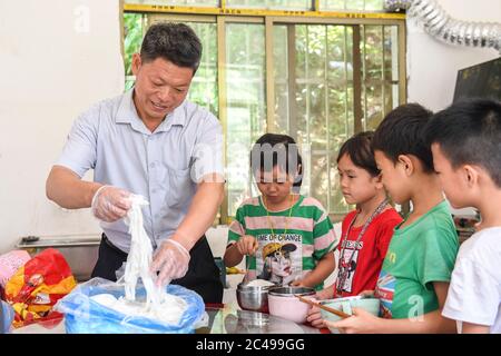 (200625) -- NINGMING, 25 giugno 2020 (Xinhua) -- Jiao Shengding prepara il pranzo per gli studenti in un luogo di insegnamento in Aidian Township della contea di Ningming, regione autonoma di Guangxi Zhuang, 23 giugno 2020. Jiao Shengding, 52 anni, è l'unico insegnante del villaggio di Zhangji, situato al confine tra Cina e Vietnam. Dopo essersi laureato alla scuola professionale secondaria della contea nel 1990, Jiao ha scelto di essere un insegnante presso il suo villaggio di Zhangji, città natale, e da allora ha insegnato lì per 30 anni. Negli ultimi tre decenni, insegnò più di 400 pupi Foto Stock