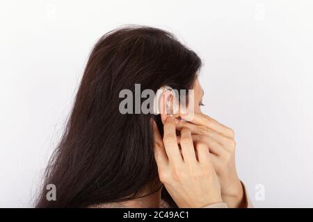 Donna che inserisce il suo apparecchio acustico Foto Stock