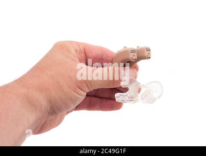 Mano dell'uomo che mostra un paio di apparecchi acustici BTE con muffa per orecchie isolata su bianco Foto Stock