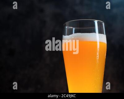 Un bicchiere di birra di grano su sfondo scuro primo piano con copyspace Foto Stock